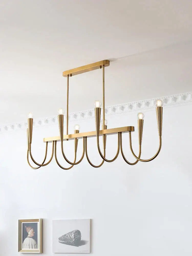 A modern brass black pendant chandelier with sleek geometric curved arms and exposed bulbs for kitchen island lighting