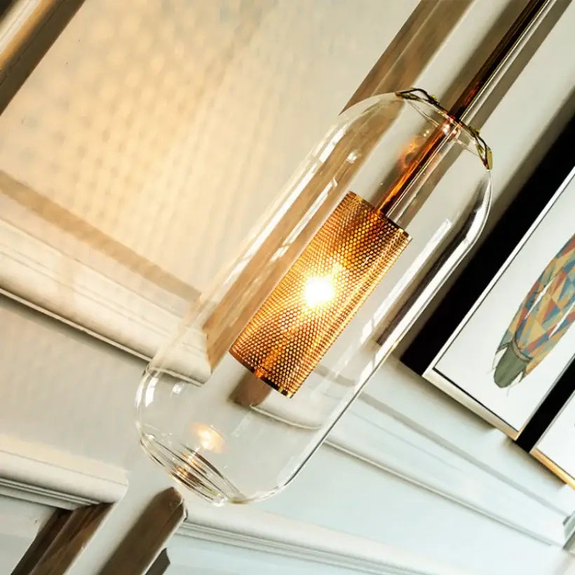 Modern brass and black wall sconce lights featuring a clear glass pendant with a gold mesh bulb holder for bedroom use