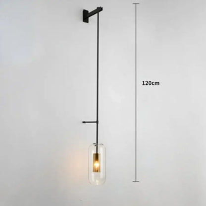 Modern brass and black wall sconce lights with a cylindrical glass shade and exposed brass filament bulb for bedrooms
