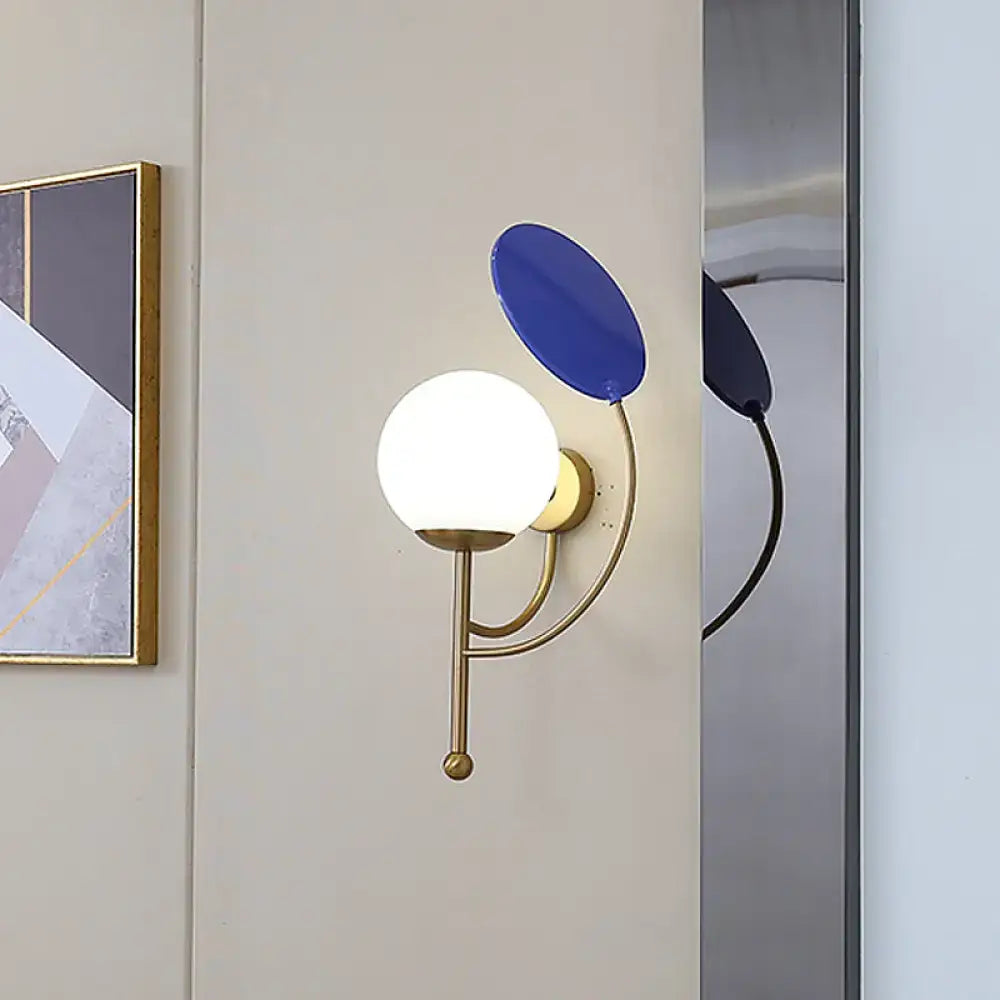 Modern brass and blue wall sconce with white frosted glass spherical bulb for bedroom lighting