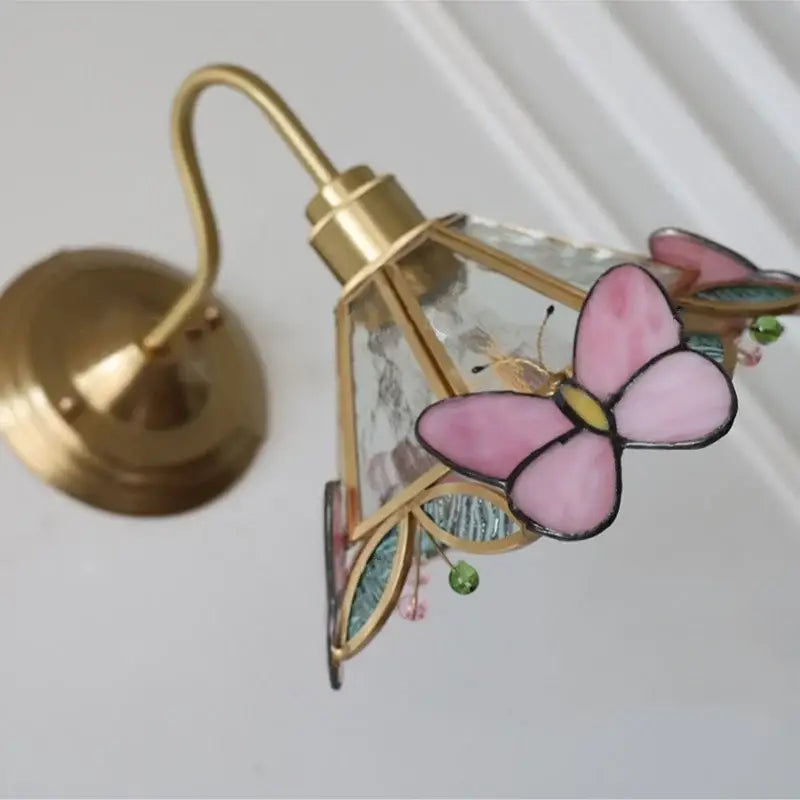 Modern brass butterfly wall sconce with pink and blue clear glass wings by decorbites for stylish bedroom lighting