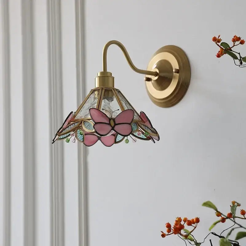 Modern brass wall sconce with pink butterfly stained glass shade featuring colorful decorbites clear glass accents