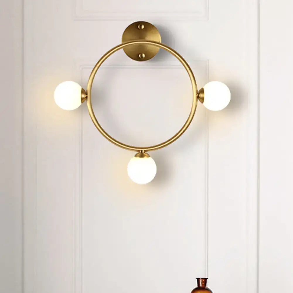 Modern brass circular wall light fixture with three frosted glass globe shades ideal for bedroom wall light fixture