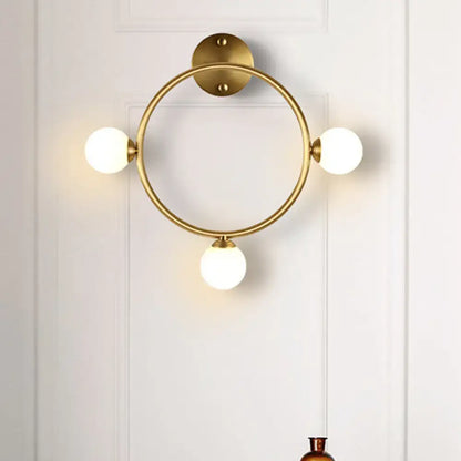 Modern brass circular wall light fixture with three frosted glass globe shades ideal for bedroom wall light fixture