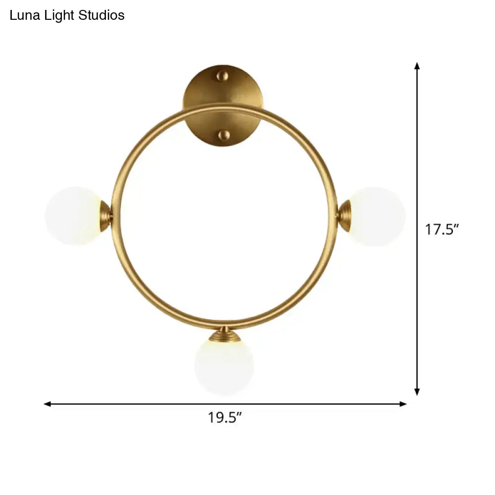 Modern brass circular wall light fixture with three frosted glass globe shades ideal for bedroom wall lighting