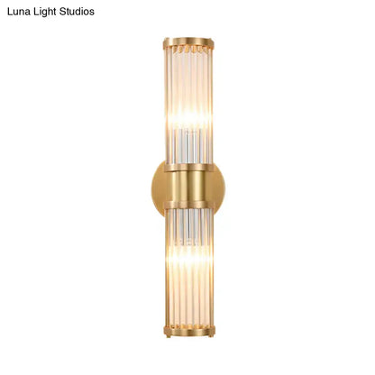 Modern brass clear crystal wall lamp with gold-toned vertical glass tubes and circular mounting plate for bedroom sconce