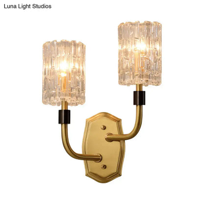 Modern brass clear glass sconce with gold-toned finish, black accents, and two textured shades for living room use