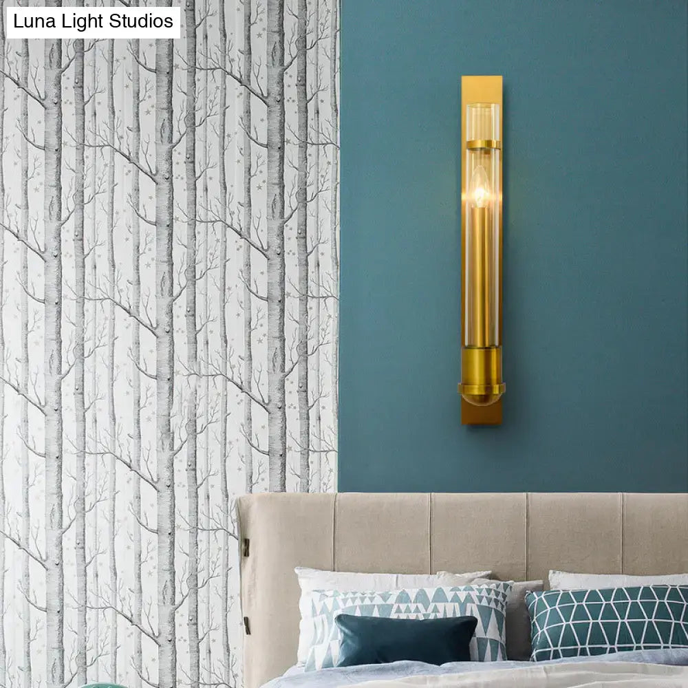 Modern brass clear glass wall sconce light fixture with gold-toned metal and exposed bulb for bedroom lighting