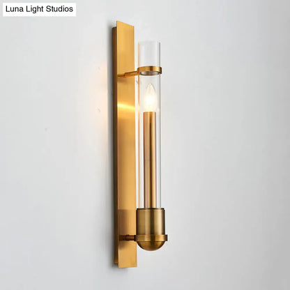 Modern brass clear glass wall sconce with gold-toned cylindrical enclosure and exposed candle bulb light fixture