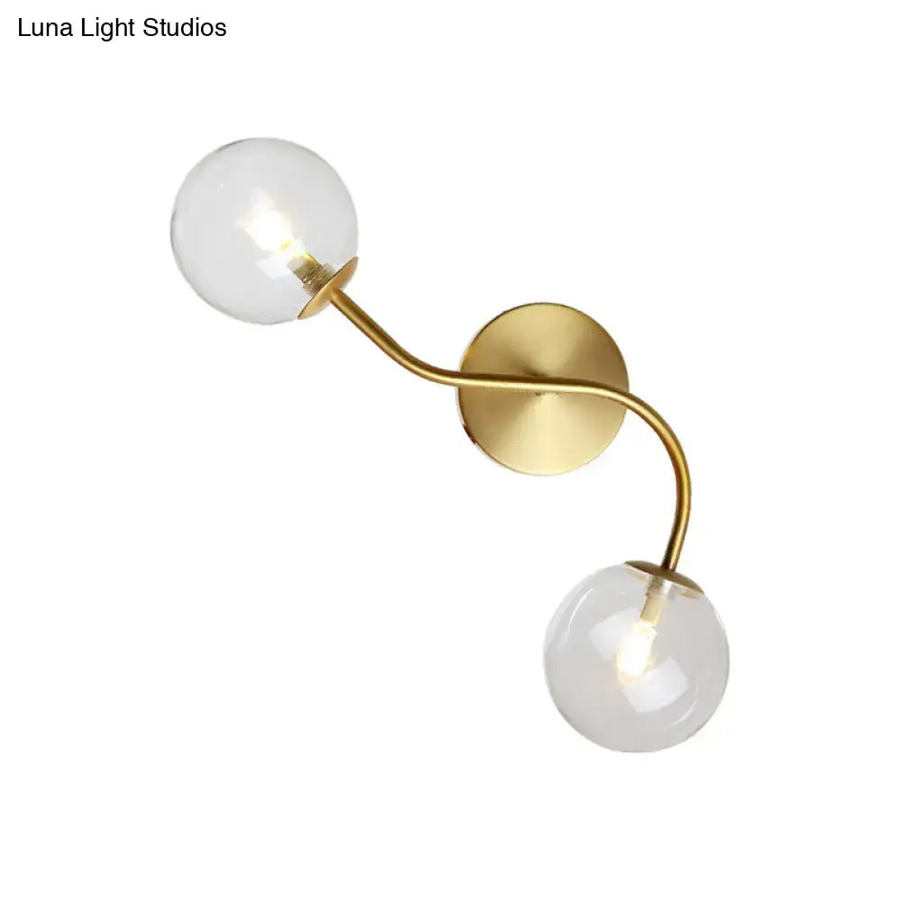 Gold-toned modern brass double globe wall lamp with clear tan glass bulbs and bulb base for stairway lighting