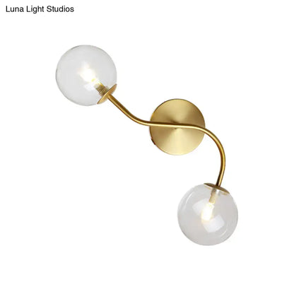 Gold-toned modern brass double globe wall lamp with clear tan glass bulbs and bulb base for stairway lighting