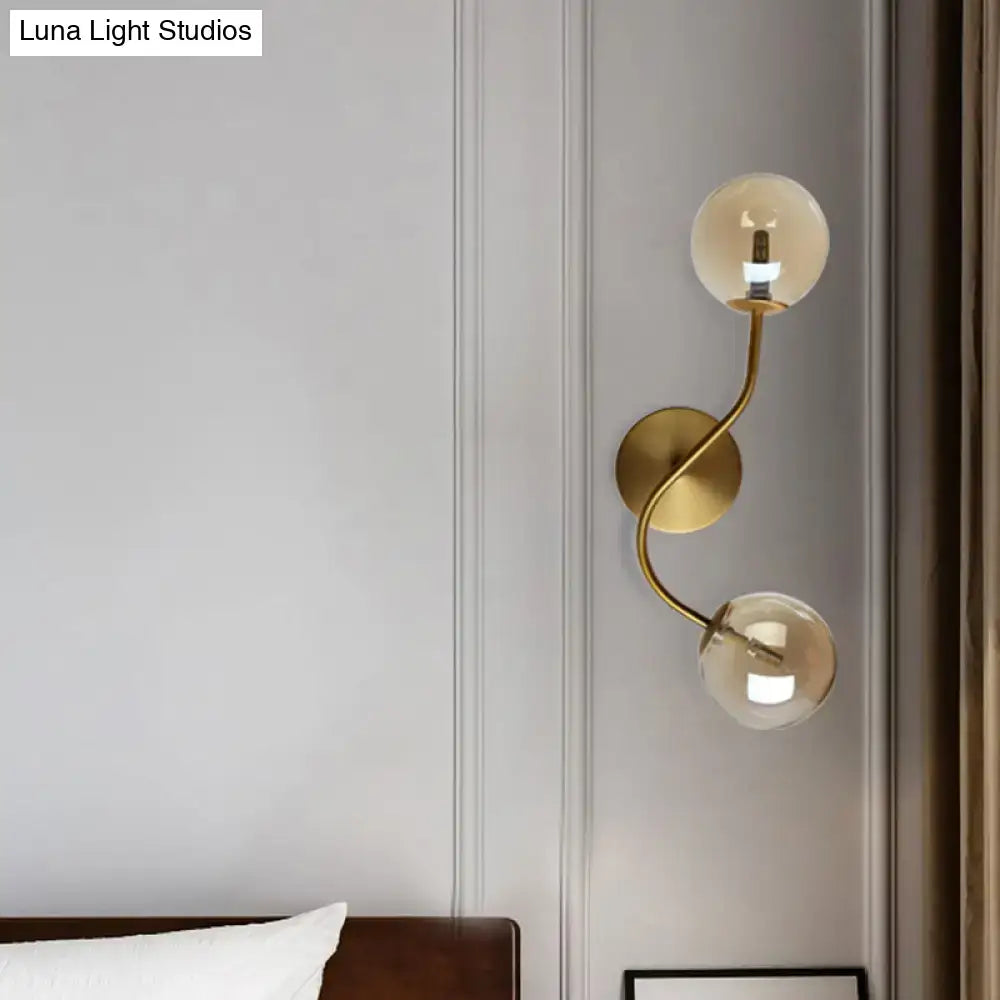 Modern brass wall lamp with clear tan glass globes and gold-toned bulb base for stairway lighting with two lights