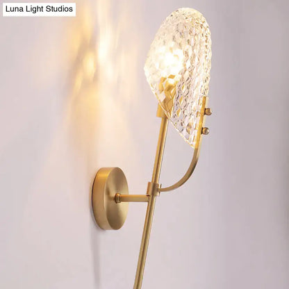 A gold-toned modern brass crystal beveled light fixture hallway sconce with a textured faceted crystal shade