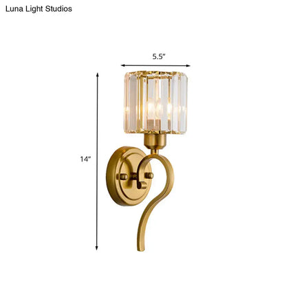 Modern brass crystal cylinder wall sconce with gold finish and curved arm featuring a crystal block cylinder shade