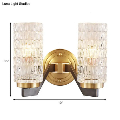 Modern brass crystal flush wall sconce with gold finish, clear textured glass cylinders, and dark metal arms wall lamp