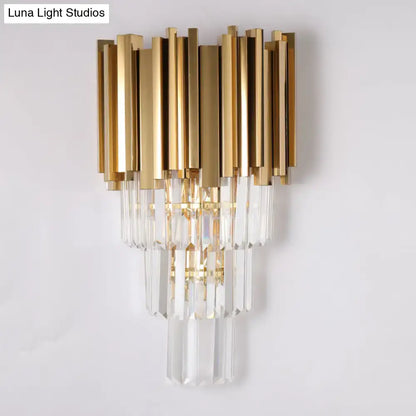 Modern brass wall lamp with gold-toned finish and cascading crystal prisms direct wired electric for living room use