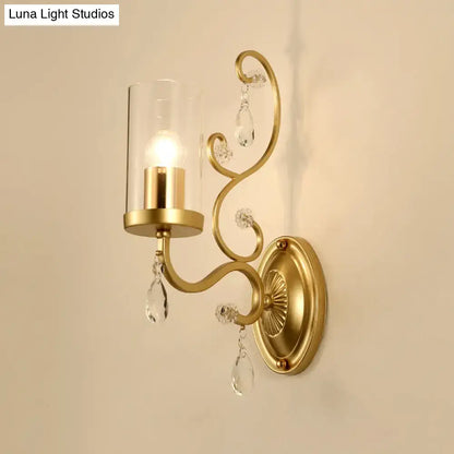 Modern brass crystal wall mounted light with gold-toned finish and clear crystal droplets in cylindrical glass shade