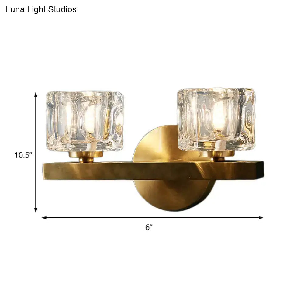 Modern brass wall sconce with two textured clear glass candle-style shades for contemporary cube flush lighting