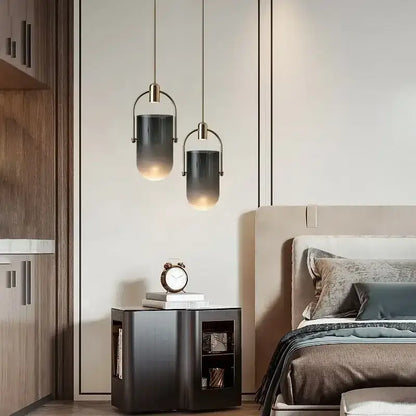 Two pendant lights with dark gray glass shades and brass frames in a modern decorbites bucket chandelier design