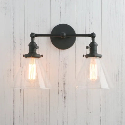 Black wrought iron wall sconce with two clear decorbites funnel glass shades and exposed filament bulbs light fixture