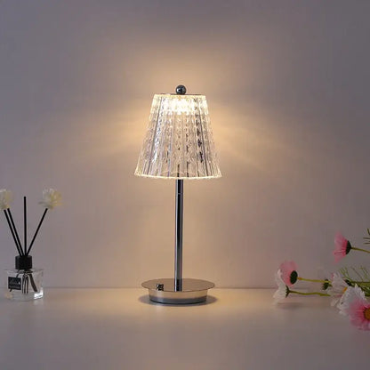 A modern brass diamond touch desk lamp with a clear faceted glass shade and polished chrome base for bedroom use