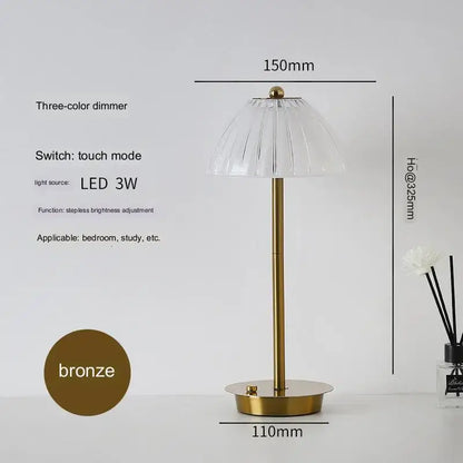 A modern brass diamond touch desk lamp with a sleek bronze finish and clear fluted glass shade featuring touch controls