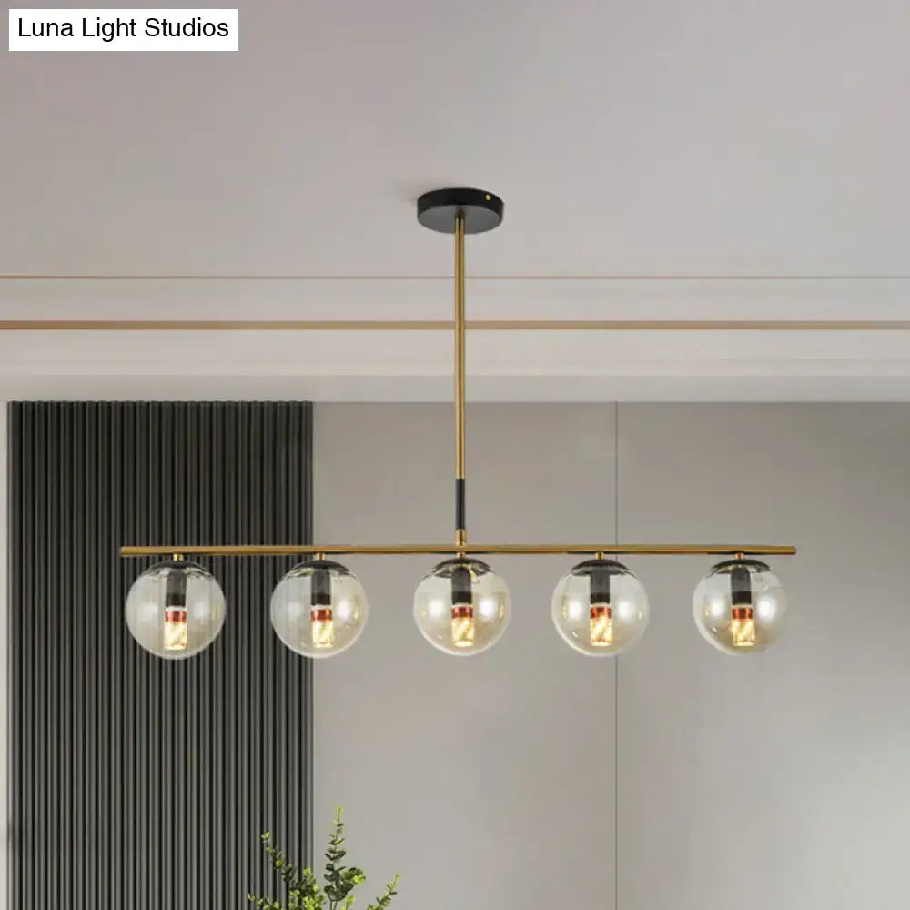 Modern brass dining room pendant light with cognac glass shades and five clear glass globe shades for elegant lighting