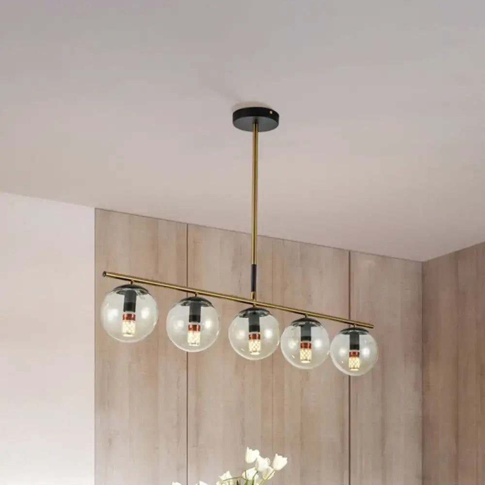 Modern brass dining room pendant light with five cognac glass shades and black accents for elegant lighting