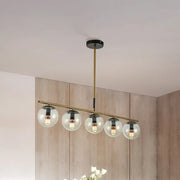 Modern brass dining room pendant light with five cognac glass shades and black accents for elegant lighting