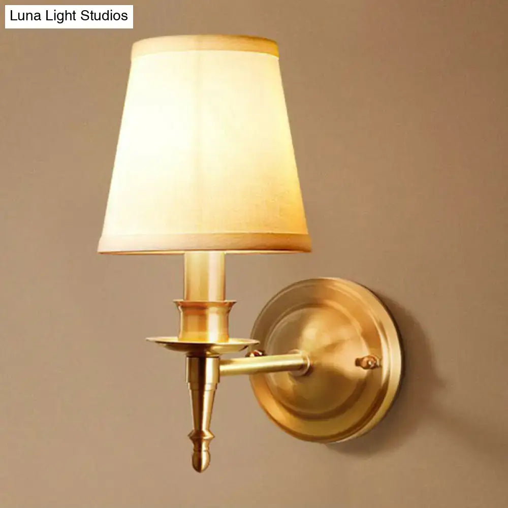 Antique brass wall light with a soft beige fabric shade designed as a modern corridor sconce