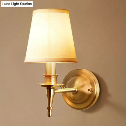 Antique brass wall light with a soft beige fabric shade designed as a modern corridor sconce