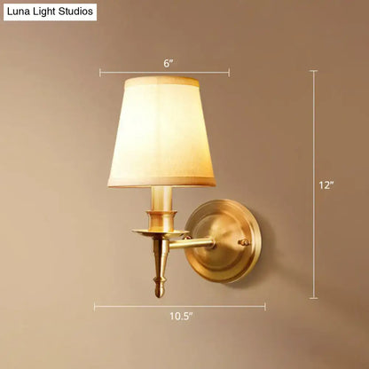 Antique brass wall light with a tapered off-white fabric shade designed for modern corridor lighting