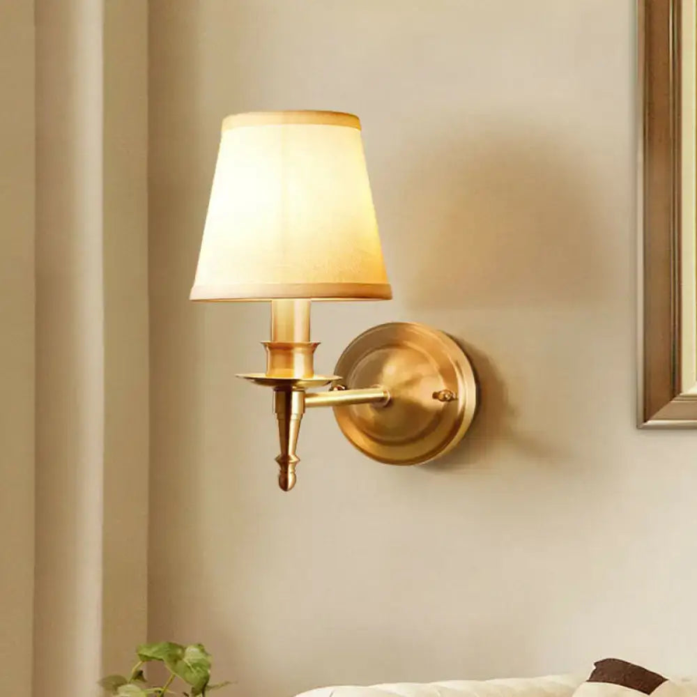 Modern brass fabric wall light with a cream-colored shade designed as a corridor sconce with a brass finish