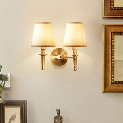 Modern brass fabric wall light with two cream-colored fabric shades for corridor or hallway lighting