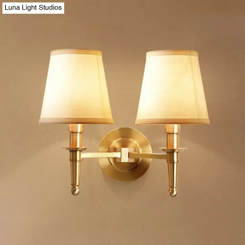 Modern brass fabric wall light corridor sconce with two cream-colored tapered fabric shades and brass finish