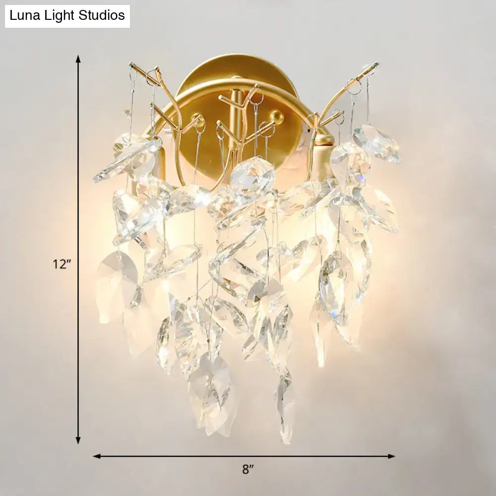 Modern brass finish wall light fixture with gold-toned sconce and cascading clear crystal leaves for bedroom use
