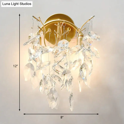 Modern brass finish wall light fixture with gold-toned sconce and cascading clear crystal leaves for bedroom use