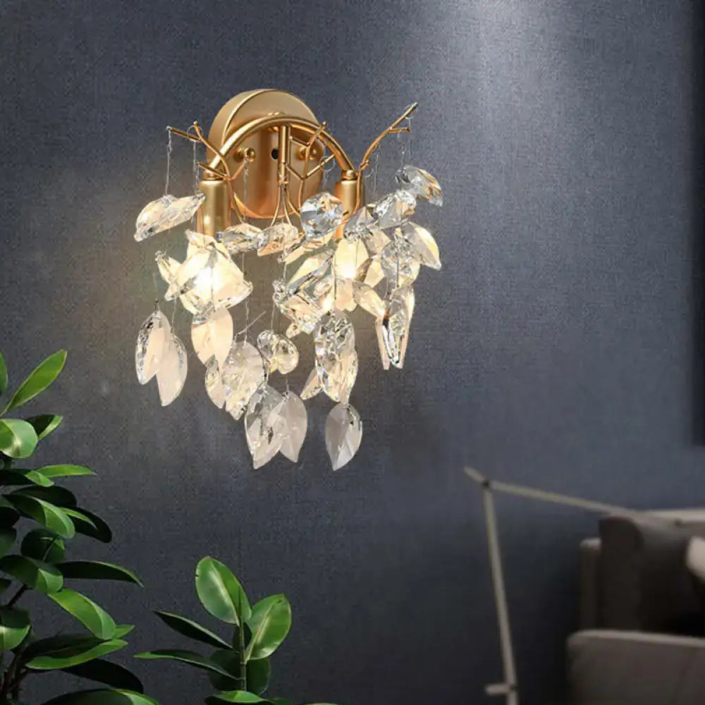 Modern brass finish wall light fixture featuring gold-toned sconce with cascading clear crystal leaves for bedroom use