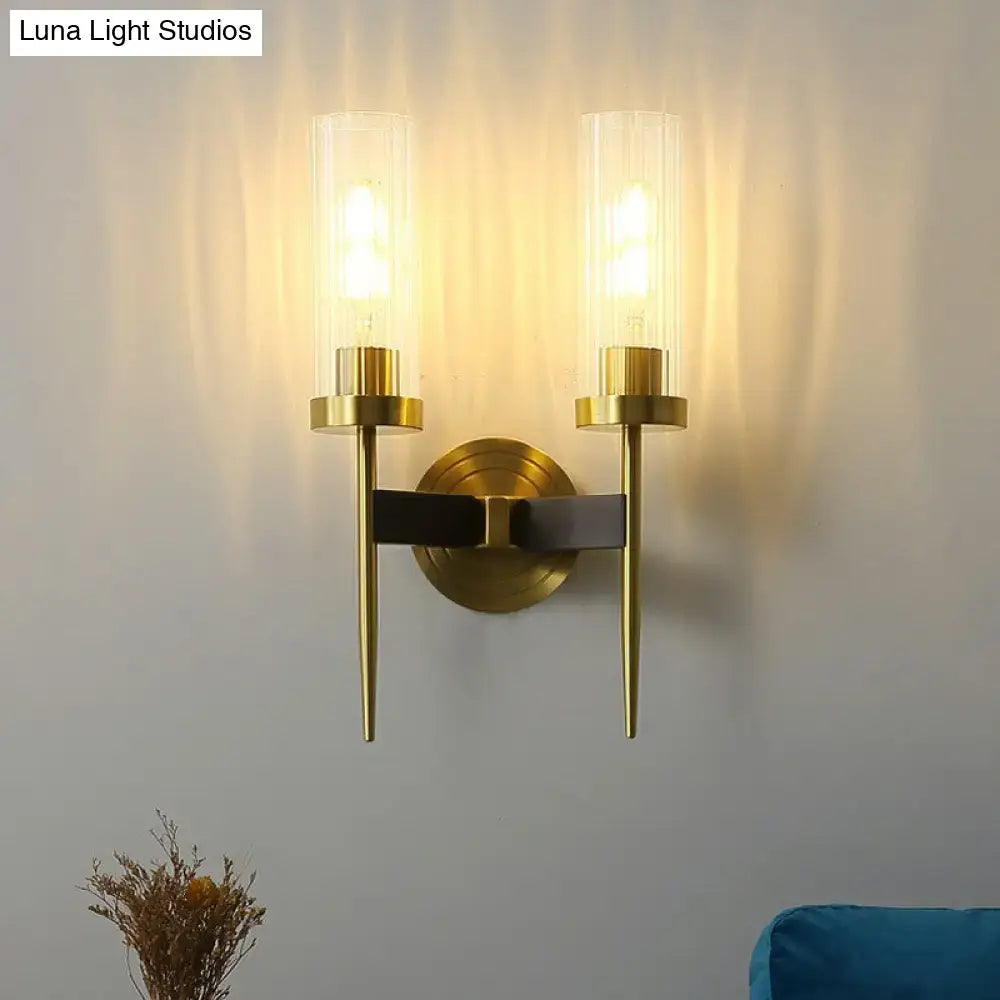 Modern brass finish glass tube wall light featuring two clear glass cylinders with warm-toned bulbs for living room