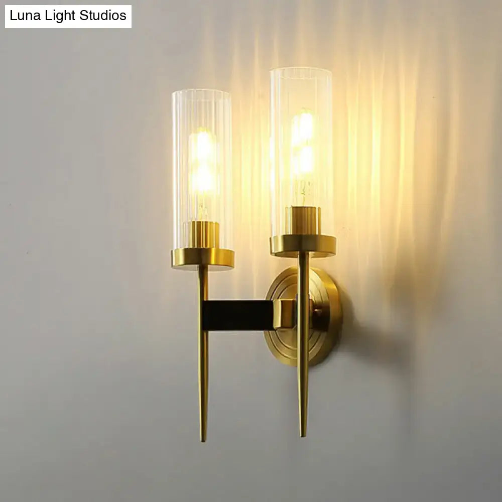 Modern brass finish glass tube wall light with gold-toned sconce and warm led bulbs mounted on black bar for living room