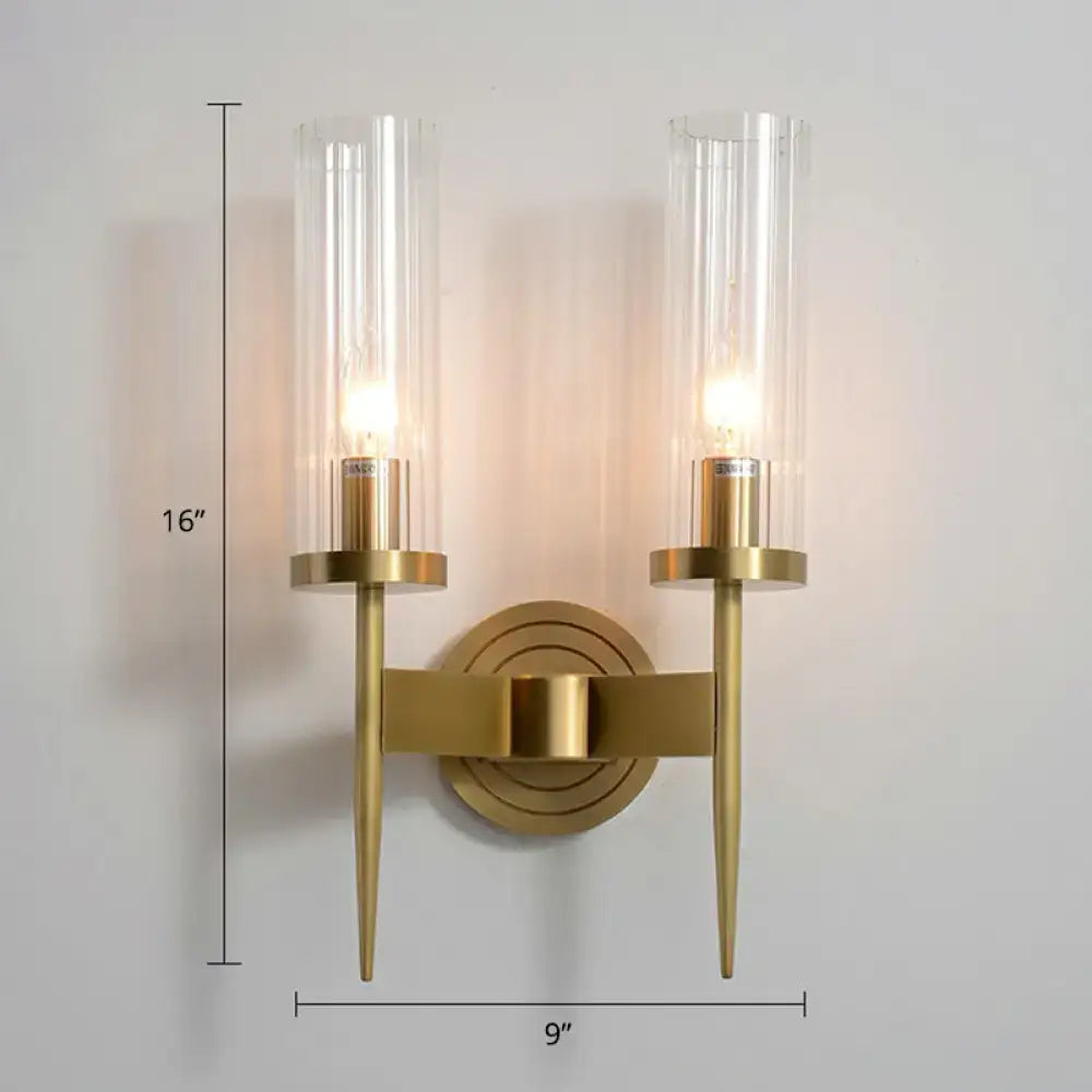 Modern brass finish wall light with gold-toned metal arms and two clear glass tube cylinders for living room use