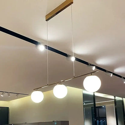 Modern brass french glass ball pendant light features three white glass globes suspended from a sleek brass ceiling mount