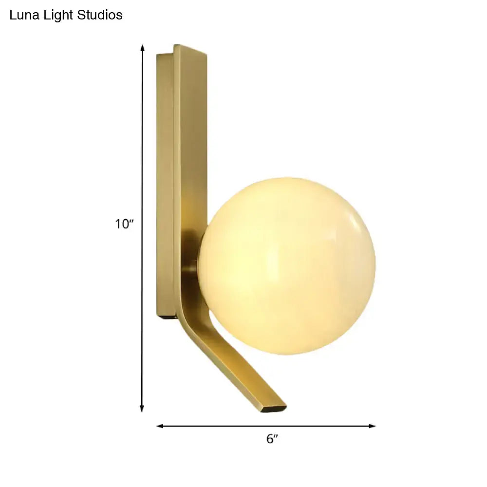 Modern brass wall lamp with curved metal backplate and frosted glass spherical shade for bedroom lighting