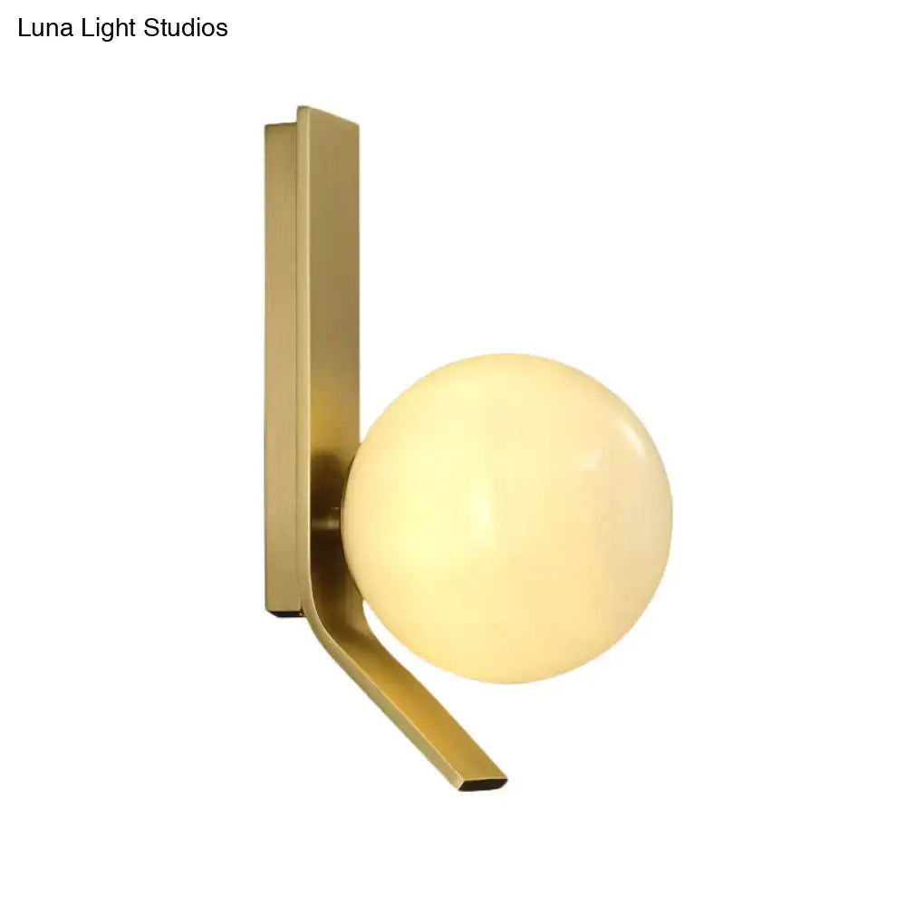 Modern brass wall lamp with curved metal backplate and frosted glass globe for bedroom lighting