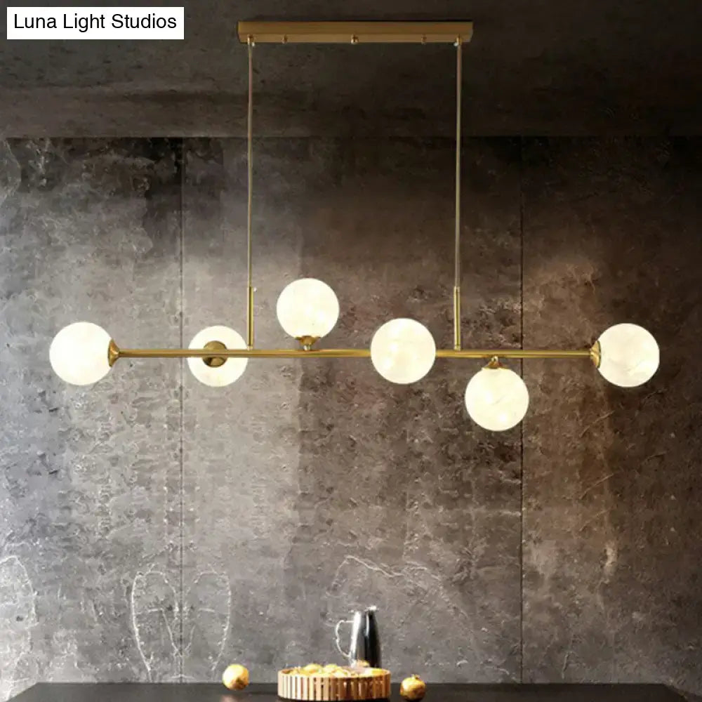 DecorBites 6-light linear dining room pendant with brass finish and smoke gray glass ball shades with frosted globes