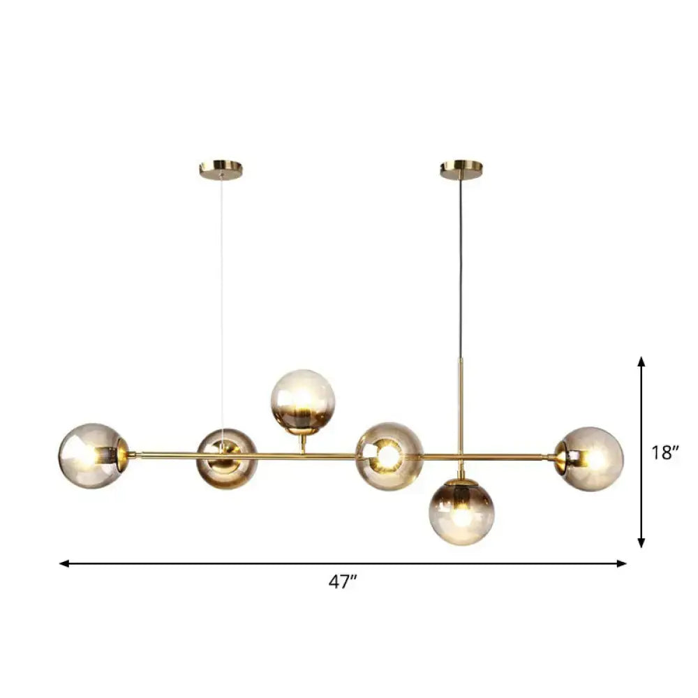 Modern brass-toned 6-light linear dining room pendant with smoke gray glass ball shades by DecorBites™