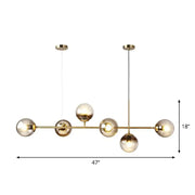 Modern brass-toned 6-light linear dining room pendant with smoke gray glass ball shades by DecorBites™