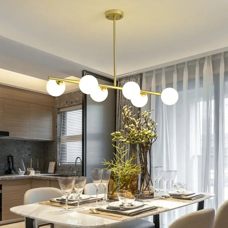 Modern brass glass ball pendant chandelier with gold-toned finish and five white spherical bulbs for dining room decorbites glass ball