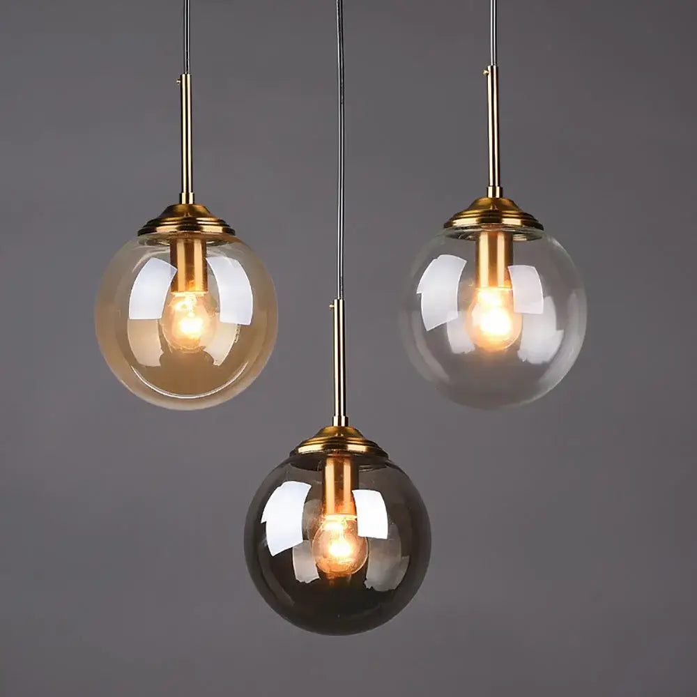 Modern brass glass ball pendant set with three globe lights featuring warm filament bulbs for bedroom lighting decorbites glass ball