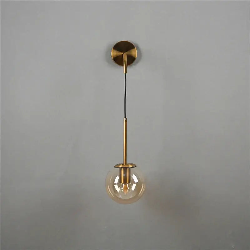 Minimalist modern brass glass ball wall lamp featuring a spherical amber globe and exposed filament bulb for bedroom decorbites wall lamp